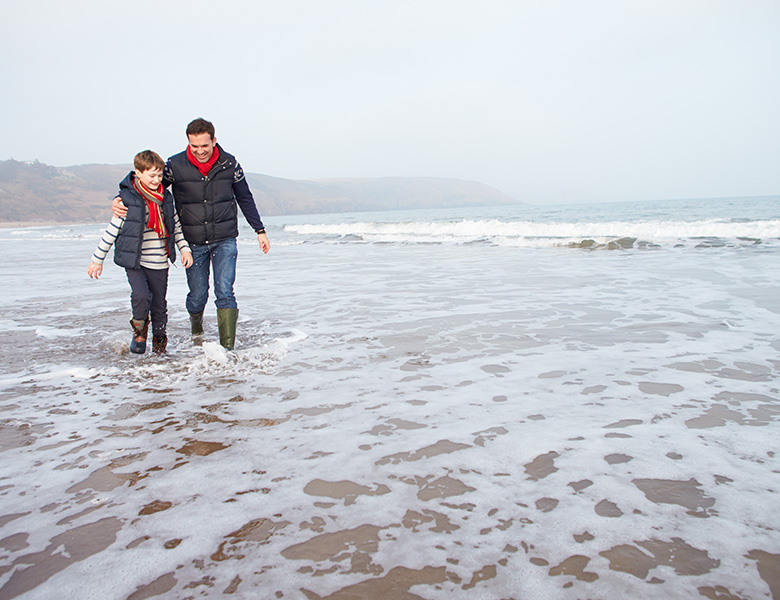 Father and son walking on a beach. Mindful parenting tips for fathers.