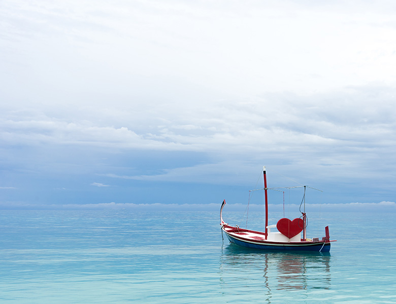 A boat in a large sea of water with a red heart, waiting for a couple to take a romantic ride.